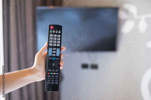 hand using remote controller for adjust Smart TV inside the modern room at home or luxury hotel