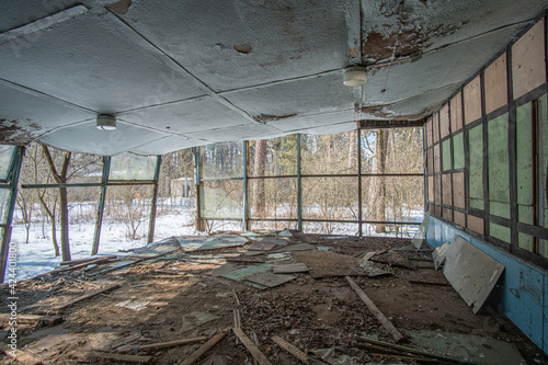 Abandoned old dining room in a camp in the woods with a roof that collapsed during the winter day.
