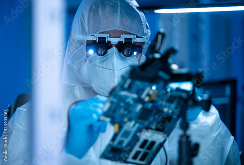 Fototapeta Naklejka Na Ścianę i Meble -  Microelectronics engineer works in a modern scientific laboratory on computing systems and microprocessors. Electronic factory worker is testing the motherboard and coding the firmware.