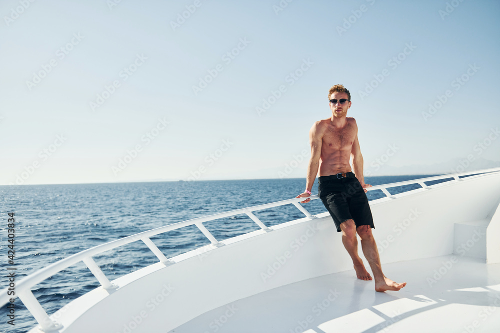 Young male tourist is on the yacht on the sea. Conception of vacation Young male tourist is on the yacht on the sea. Conception of vacation