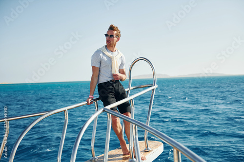 Posing for a camera. Young male tourist is on the yacht on the sea. Conception of vacation