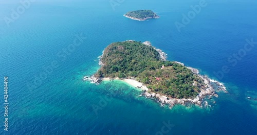 Aerial: forest of palm trees on a tropical island with bright white sand beach. In the bright and dark turquoise sea. from left to right wide angle.