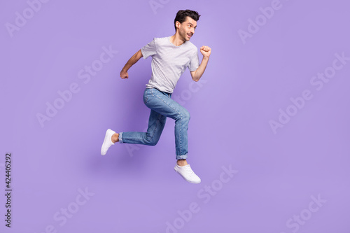 Profile photo of guy jump run look empty space wear black t-shirt jeans footwear isolated violet background