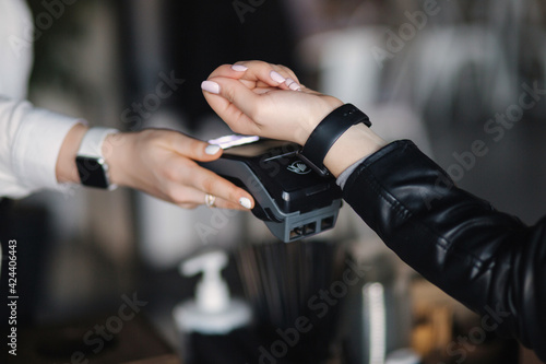 Female customer making wireless or contactless payment using smartwatch. Closeup of hands during payment. Store worker accepting payment over nfc technology