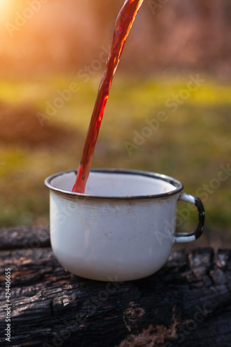 Pours hot tea into a mug. Close-up. Concept for outdoor activities, hot drink, hike, travel. 