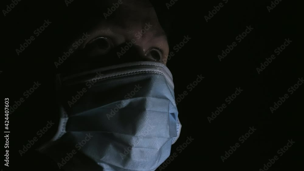 The lady inside the black room wearing the face mask as seen on a closer look. black background The lady inside the black room wearing the face mask as seen on a closer look. black background