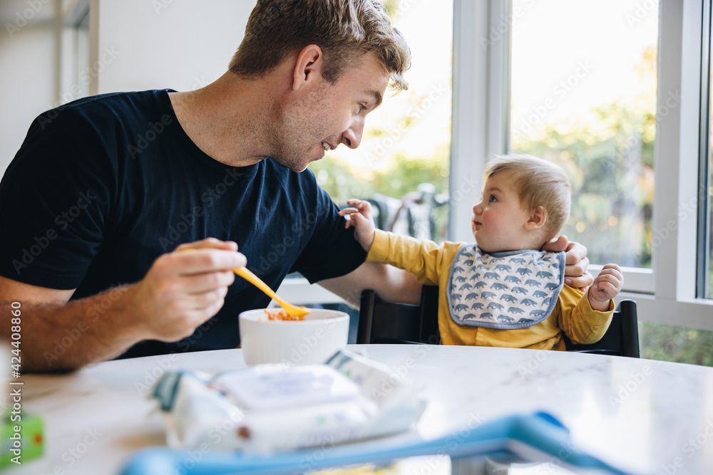 Man on paternity leave feeding his baby - obrazy, fototapety, plakaty 