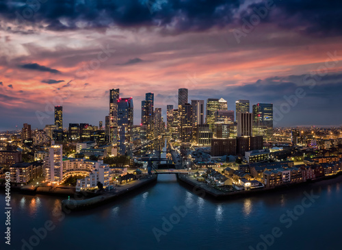 Aerial, panoramic view to the modern skyline of the financial district Canary Wharf in London, United Kingdom, with the illuminated skyscrapers just after sunset