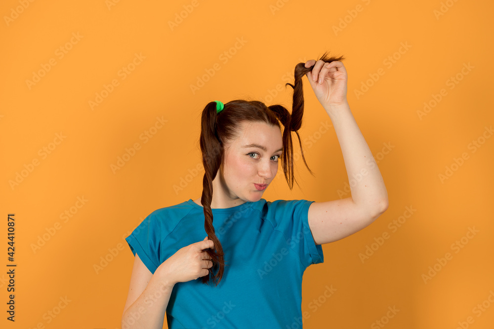 A girl with ponytails in a blue shirt and on a yellow background A girl with ponytails in a blue shirt and on a yellow background