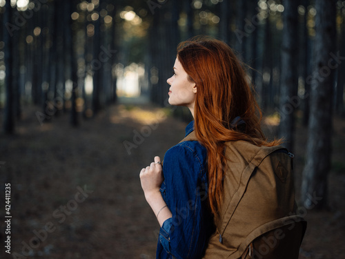 Happy traveler with a backpack on her back is resting in nature in a pine forest © SHOTPRIME STUDIO
