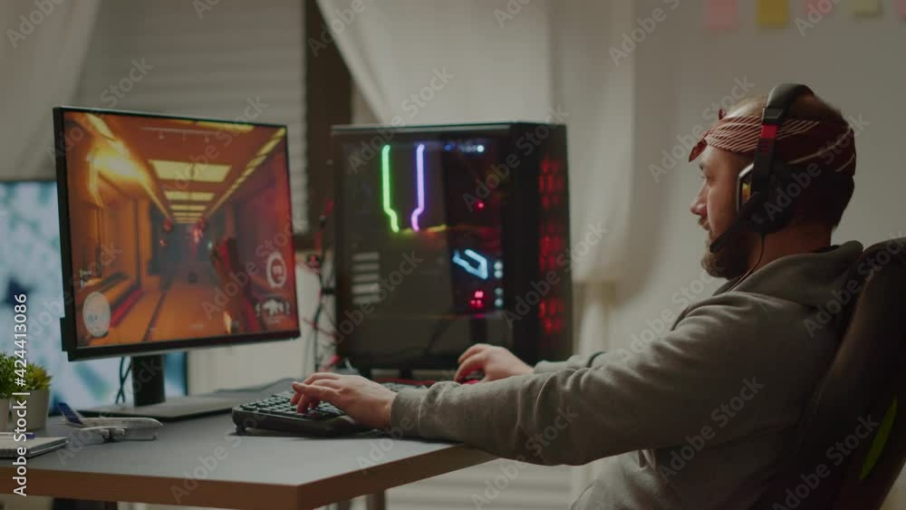 Joyful gamer celebrating victory winning first person shooter online video game on RGB powerful computer raising hands. Pro cyber streaming performing during gaming tournament, esport championship Joyful gamer celebrating victory winning first person shooter online video game on RGB powerful computer raising hands. Pro cyber streaming performing during gaming tournament, esport championship