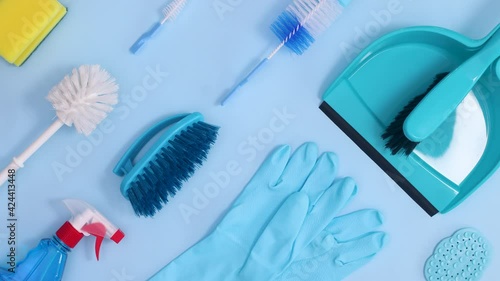 Household cleaning tools and supplies make creative pattern on bright blue background. Stop motion flat lay