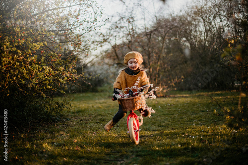 Funny girl riding a bike in the park in early spring