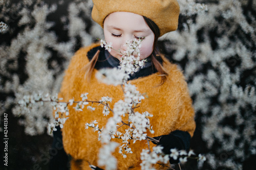 Little girl in early spring inhaling the scent of a blossoming tree