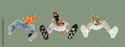 Photography Young stylish people in modern street style outfit isolated on green background, view from the bottom