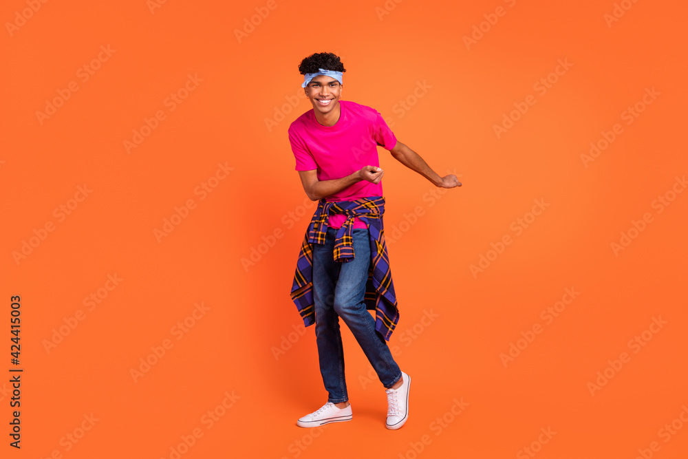Full length body size photo of happy young man dancing on weekend laughing in stylish clothes isolated on vivid orange color background
