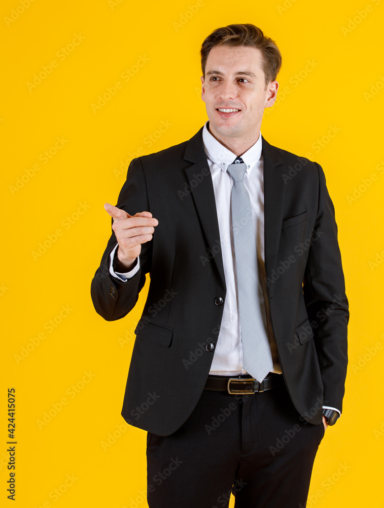 Portrait half body of handsome and executive look french businessman in black suit pointing finger to blank space in advertising pose. Successful and happy business man concept on yellow background Portrait half body of handsome and executive look french businessman in black suit pointing finger to blank space in advertising pose. Successful and happy business man concept on yellow background