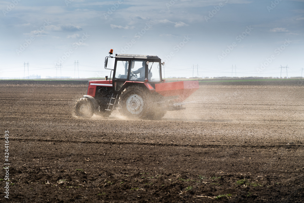 Fototapeta premium Tractor spreading artificial fertilizers
