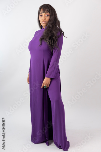 Beautiful African American Model in traditional Vietnamese purple au dai dress on a white studio background. Full length side on  photo