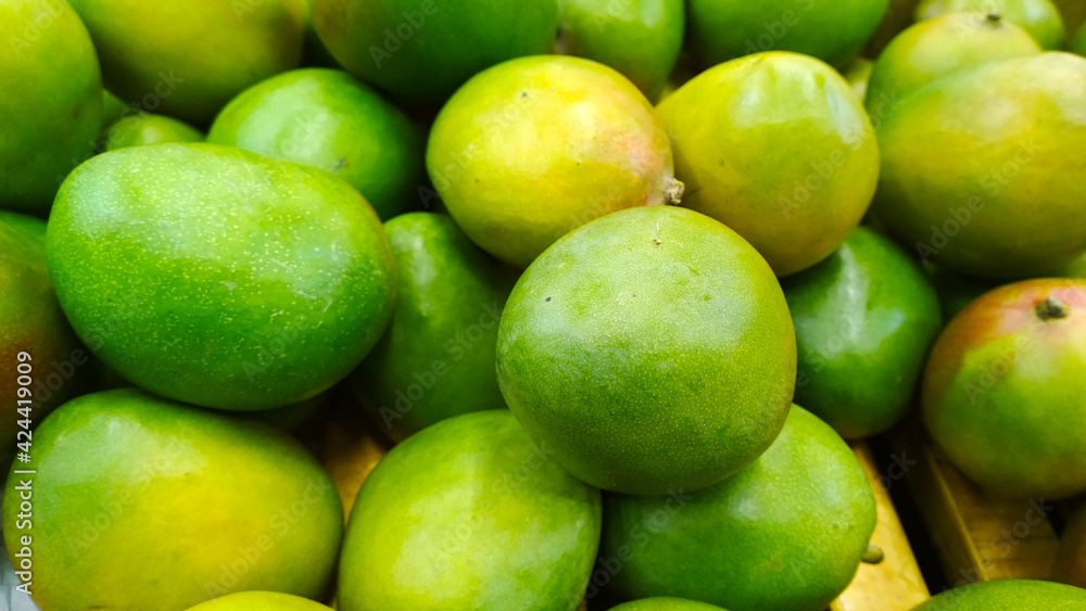 Pile of green mango background. Grocery store. Shelves with organic natural fruit in supermarket or farmer market. Fresh food. Retail industry. Discount and sale. Greengrocer. Healthy eating. Diet. Pile of green mango background. Grocery store. Shelves with organic natural fruit in supermarket or farmer market. Fresh food. Retail industry. Discount and sale. Greengrocer. Healthy eating. Diet.