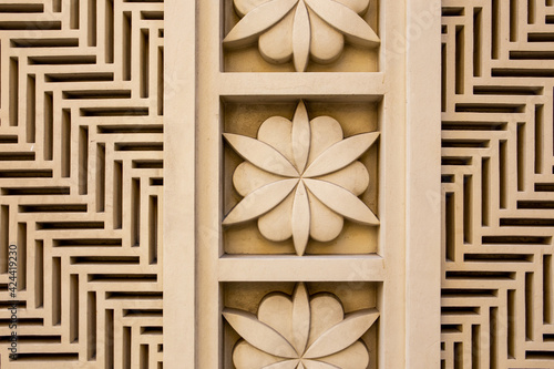 Photography Arabic style carved stone openwork and relief, with floral patterns and geometric shapes and lines, on a building facade in Dubai JBR, UAE