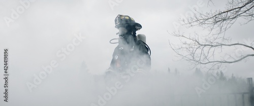 Photo Silhouette of American female firefighter in traditional helmet and full gear standing in the smoke