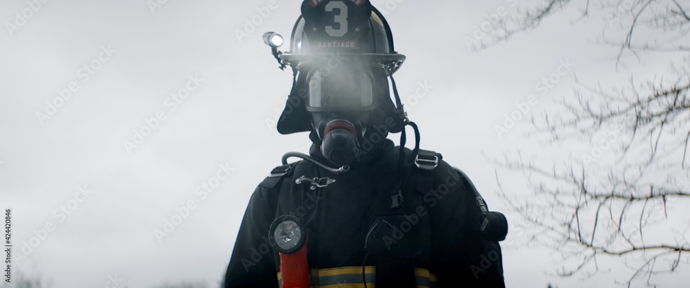 Hero shot portrait of American male firefighter in full gear standing in the smoke. Shot with 2x anamorphic lens Hero shot portrait of American male firefighter in full gear standing in the smoke. Shot with 2x anamorphic lens