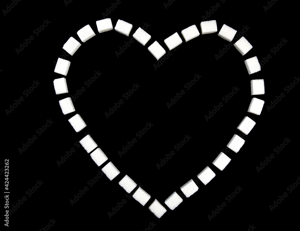 Fototapeta premium Heart lined with sugar cubes on a black background.