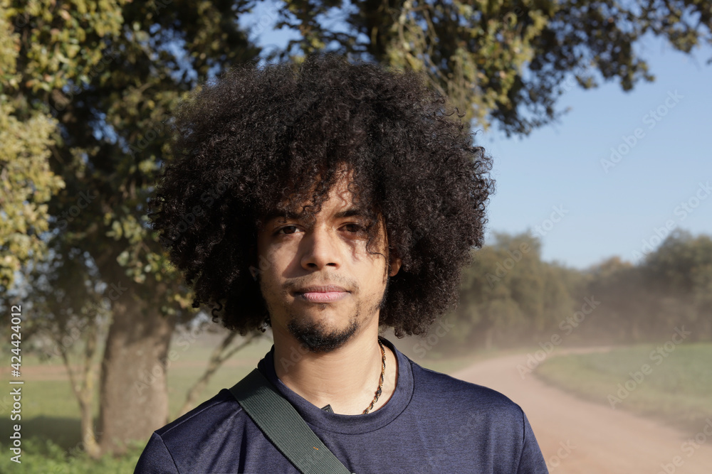young black man with afro looking at the camera in an open air field. Portrait of afro men young black man with afro looking at the camera in an open air field. Portrait of afro men