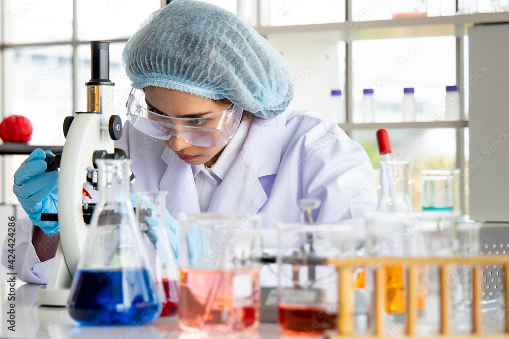 Cute young Asian researcher wearing safety protective eyeglasses working with lab equipment in the laboratory room Cute young Asian researcher wearing safety protective eyeglasses working with lab equipment in the laboratory room