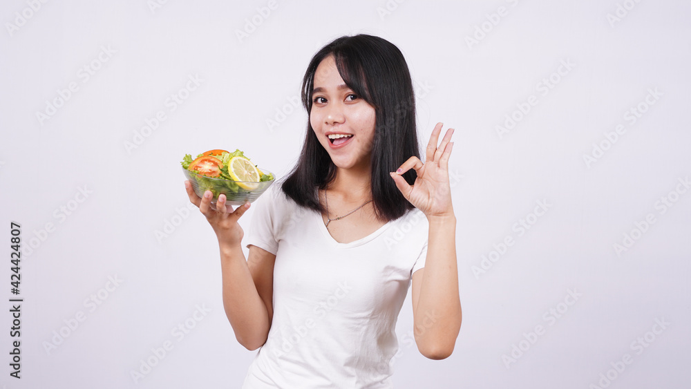 asian women and okay finger at a bowl of fresh mixed vegetables salad with isolated white background asian women and okay finger at a bowl of fresh mixed vegetables salad with isolated white background