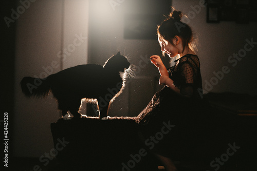 Little girl in black dress with black cat at home