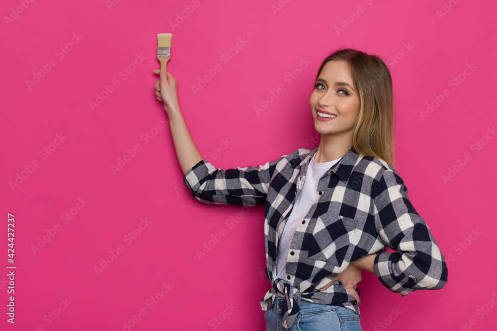 Beautiful Young Woman Is Painting Pink Wall And Smiling Beautiful Young Woman Is Painting Pink Wall And Smiling