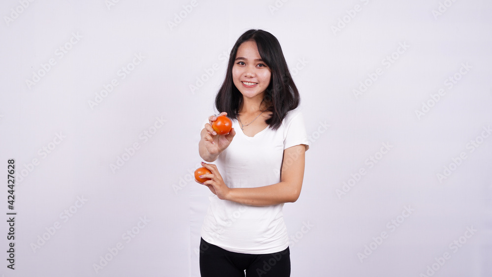 Close up beautiful asian women with a tomato isolated on white background Close up beautiful asian women with a tomato isolated on white background