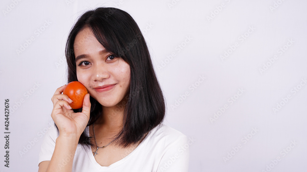 Close up beautiful asian women with a tomato isolated on white background Close up beautiful asian women with a tomato isolated on white background