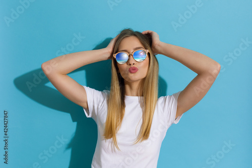 Young Blond Woman In White Shirt And Sunglasses Is  Sending A Kiss
