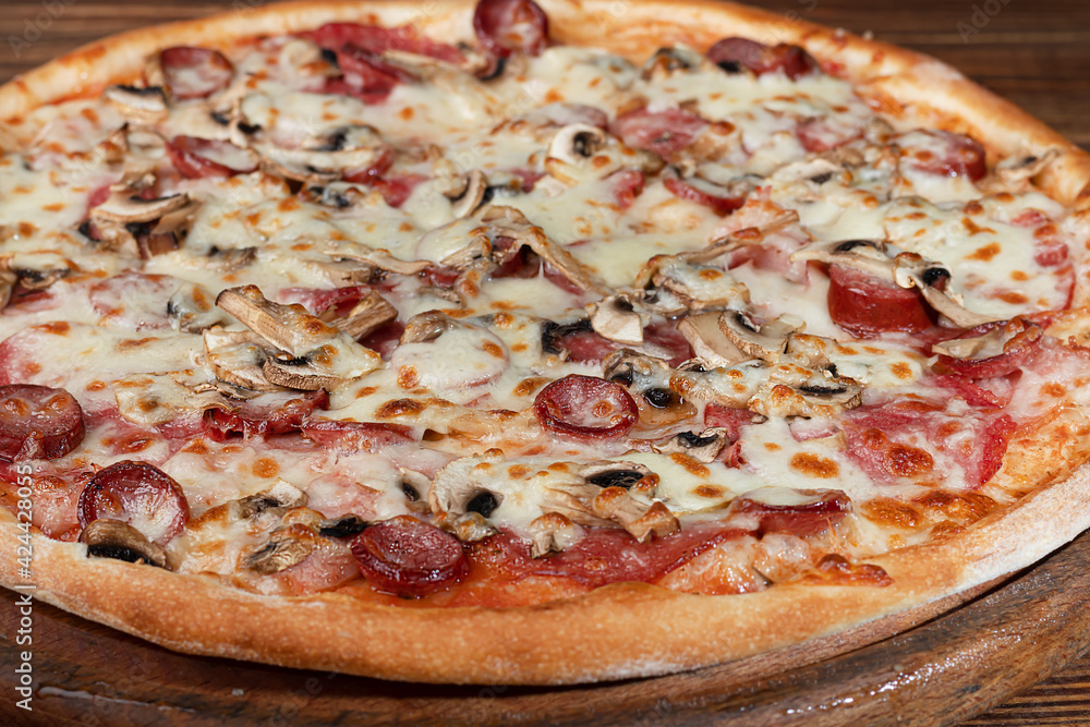 Pizza with bacon cheese and herbs on a wooden plate with cheese and cherry tomatoes. On a wooden background. Pizza with bacon cheese and herbs on a wooden plate with cheese and cherry tomatoes. On a wooden background.