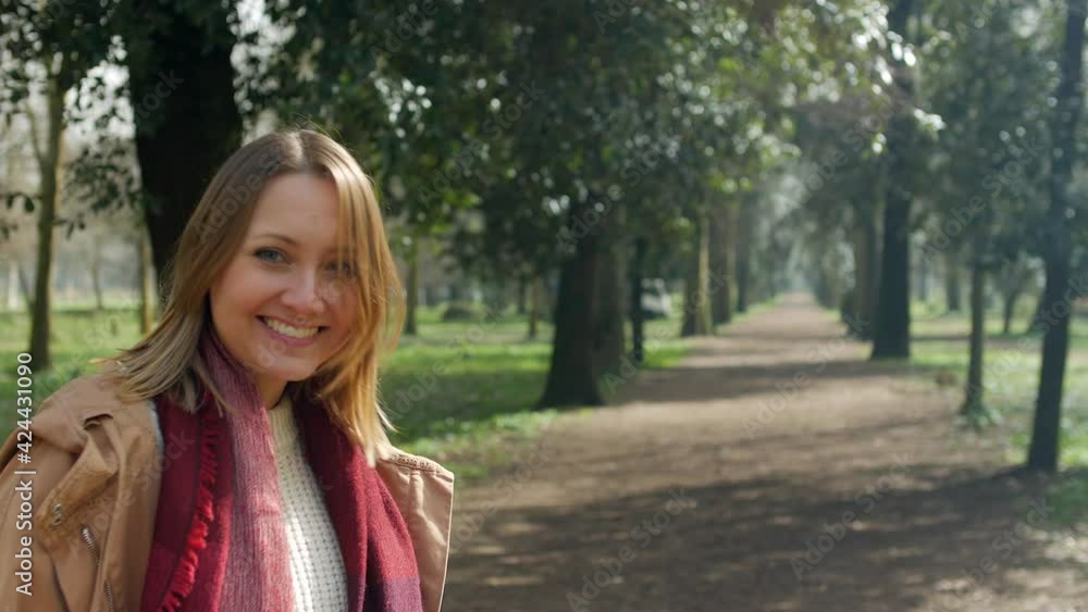 Happy young woman walking in park, turning to camera Happy young woman walking in park, turning to camera