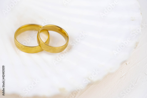 Two golden wedding rings close up on white background. Wedding invitation card concept. 