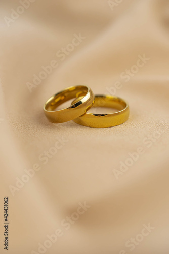 Two golden wedding rings close up on the cloth. Wedding invitation card concept. 
