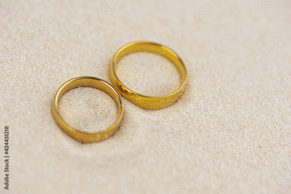 Two golden wedding rings close up on sand. Wedding on the beach invitation card concept. Two golden wedding rings close up on sand. Wedding on the beach invitation card concept.