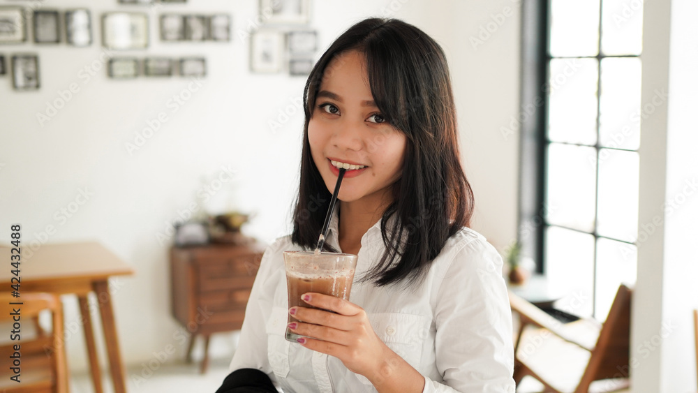 Beautiful young asian businesswoman in suit standing holding brown coffee cup in caffe while having a coffee break. Beautiful young asian businesswoman in suit standing holding brown coffee cup in caffe while having a coffee break.