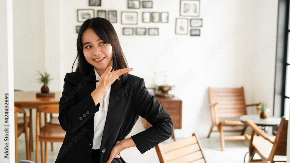 Beautiful young asian business woman in suit and pointing finger hands up at office Beautiful young asian business woman in suit and pointing finger hands up at office