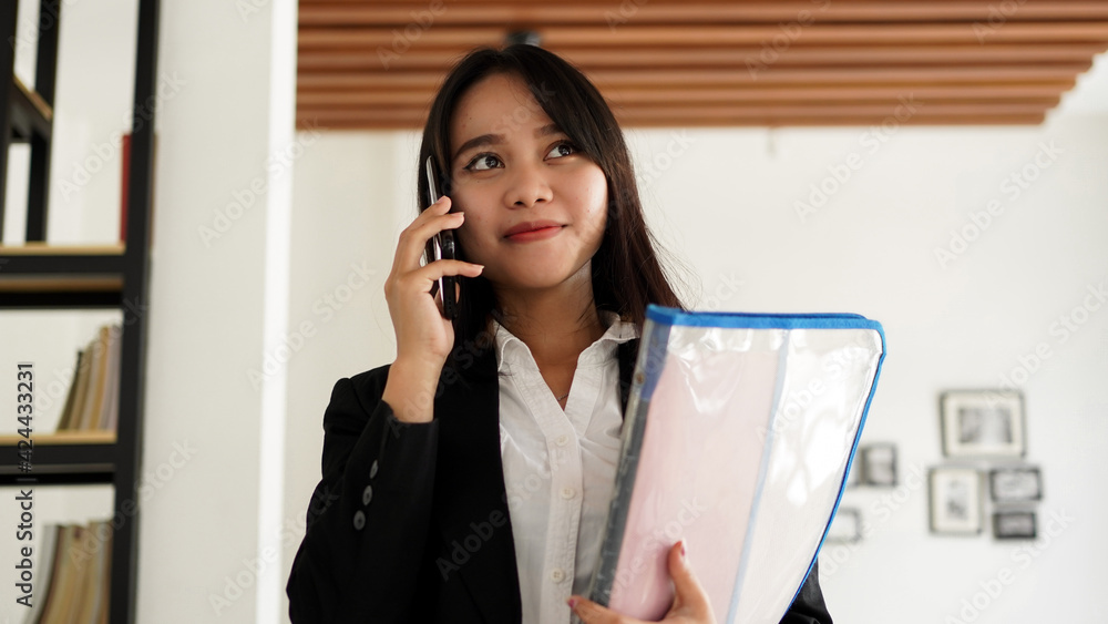 Beautiful young asian business woman in suit standing at cafe calling with phone and Brown envelope Beautiful young asian business woman in suit standing at cafe calling with phone and Brown envelope