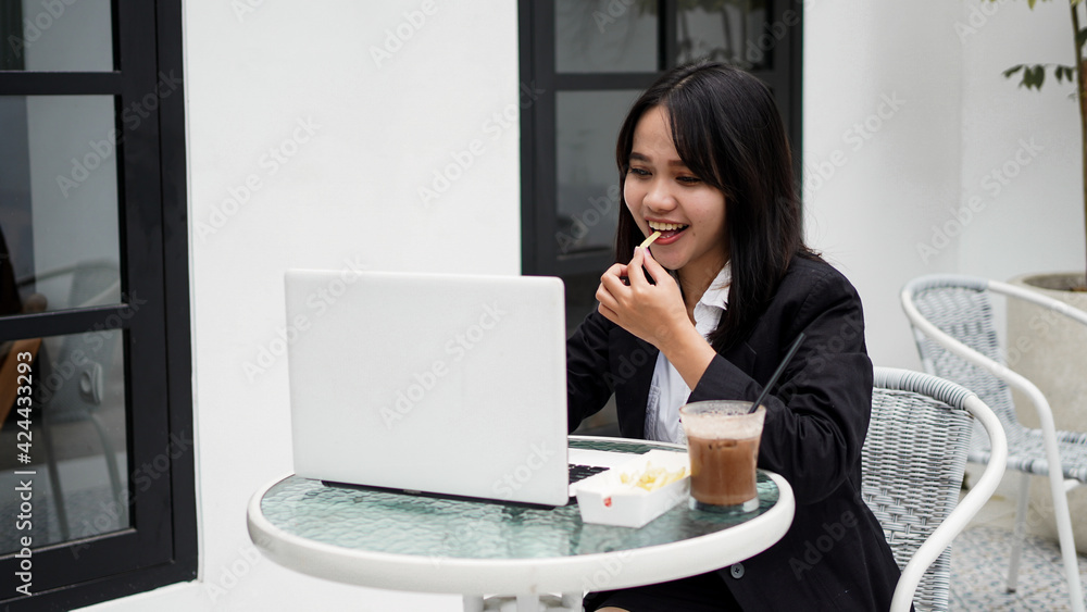 Asian business woman eating and working with his laptop at cafe Asian business woman eating and working with his laptop at cafe