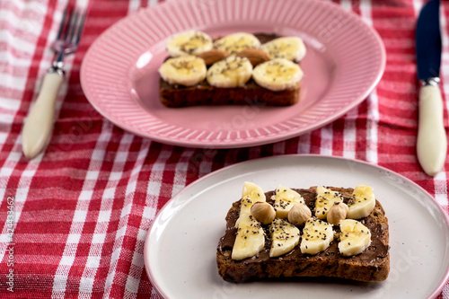 Toasted whole wheat bread with chocolate nuts paste nutella topping, banana, chia seeds, almonds and hazelnuts toast. Healthy proper nutrition for breakfast