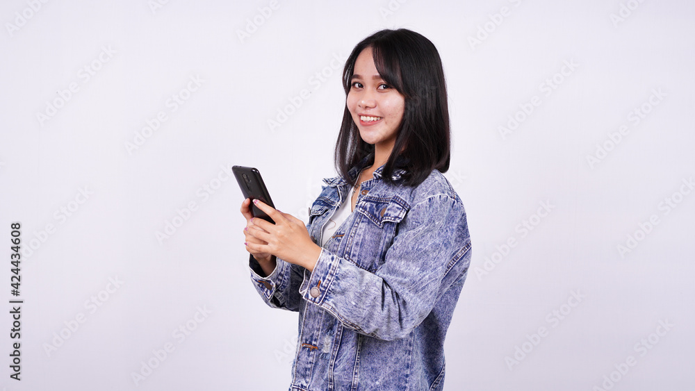 Asian women smiling wearing jeans jacket and holding phone with isolated white background Asian women smiling wearing jeans jacket and holding phone with isolated white background