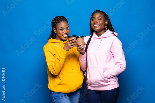 African woman having fun with her best friend frink coffee to go on blue background. photo