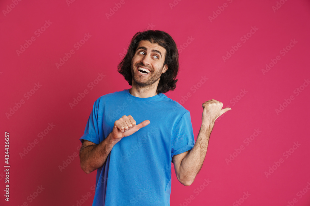 Excited brunette man pointing fingers aside and smiling Excited brunette man pointing fingers aside and smiling