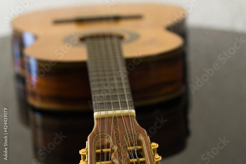 blurred viola caipira Brazilian ten strings country guitar with focus in the arm  over piano with blurry background
 photo